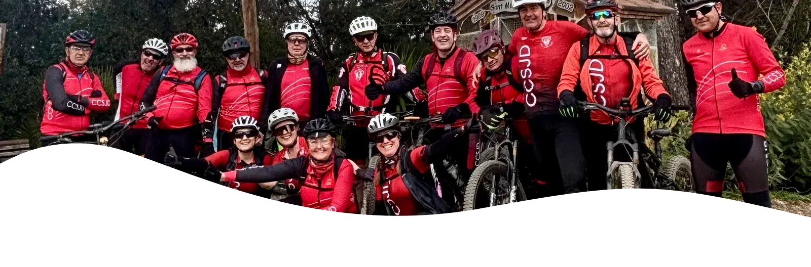 I membri del Club Ciclista Sant Joan Despí con la divisa rossa del club, in piedi con le loro mountain bike su uno sterrato nel bosco dopo un'uscita di gruppo.